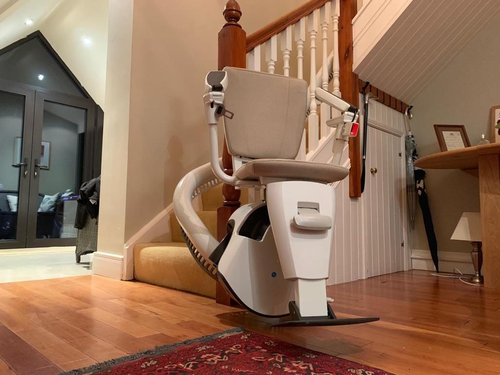 Stairlifts in Northern Ireland: Curved stairlift rail wrapping round the bottom step in a hallway with wooden floors