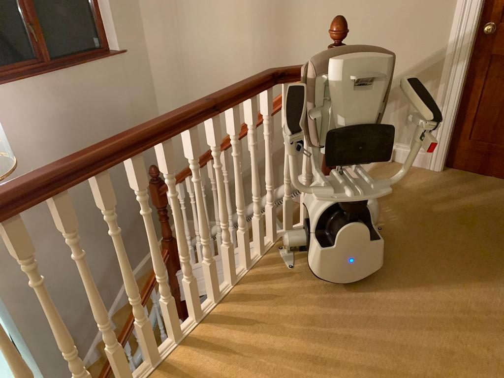 Stairlifts in Northern Ireland: Curved stairlift parked on an upstairs landing with the seat folded