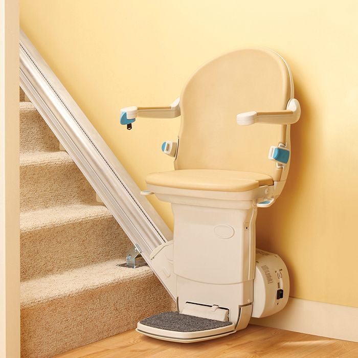 Stairlifts in Northern Ireland: Simplicity straight stairlift with a cream seat parked at the foot of a carpeted staircase